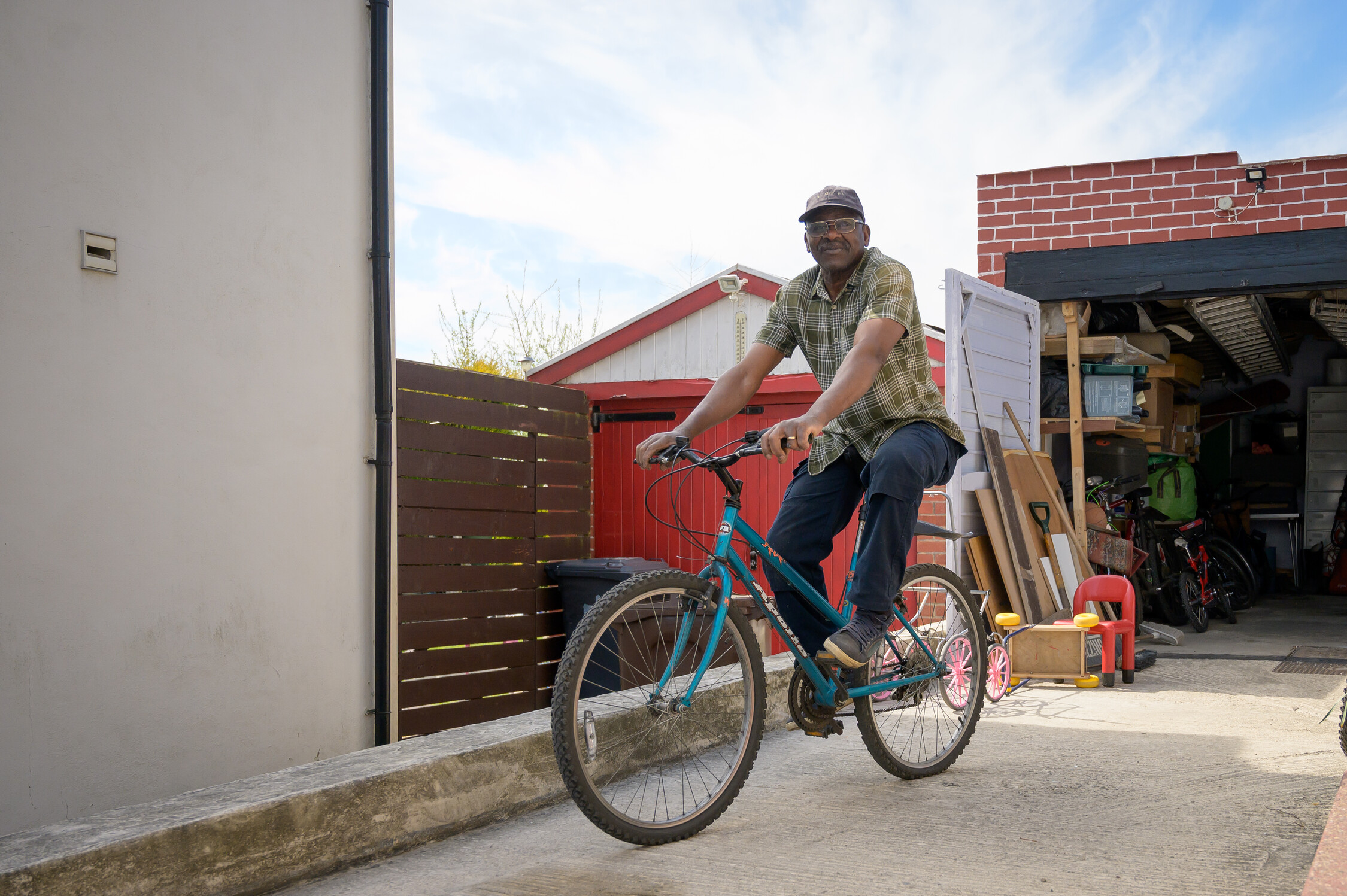 Man is on a bike in front of his open garage on his driveway.