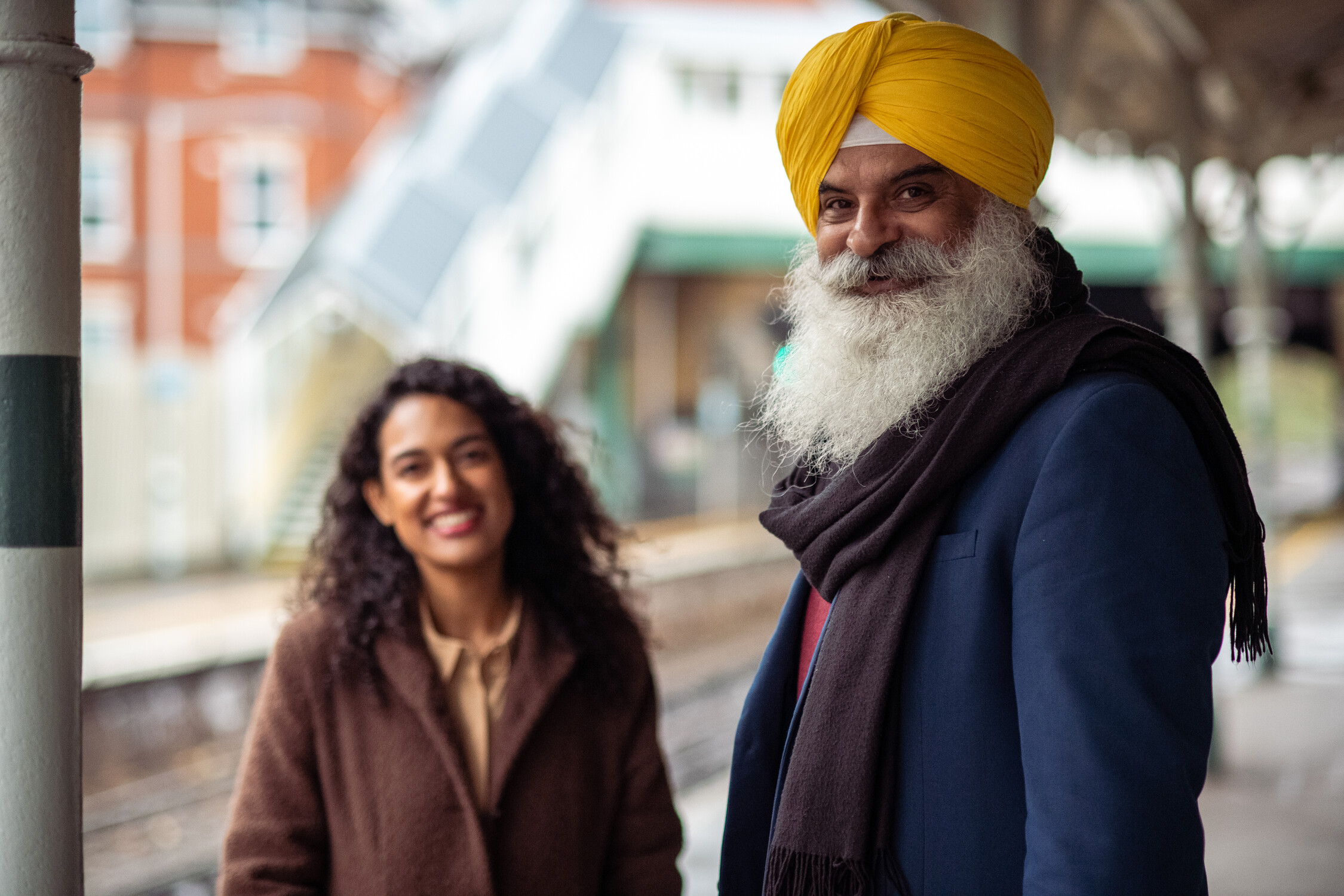 A man and woman together at a train station smiling