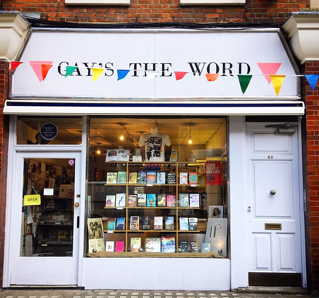 Gays the Word bookshop store front. The front of the shop is white and there is rainbow bunting in front. Lots of books are in the window.