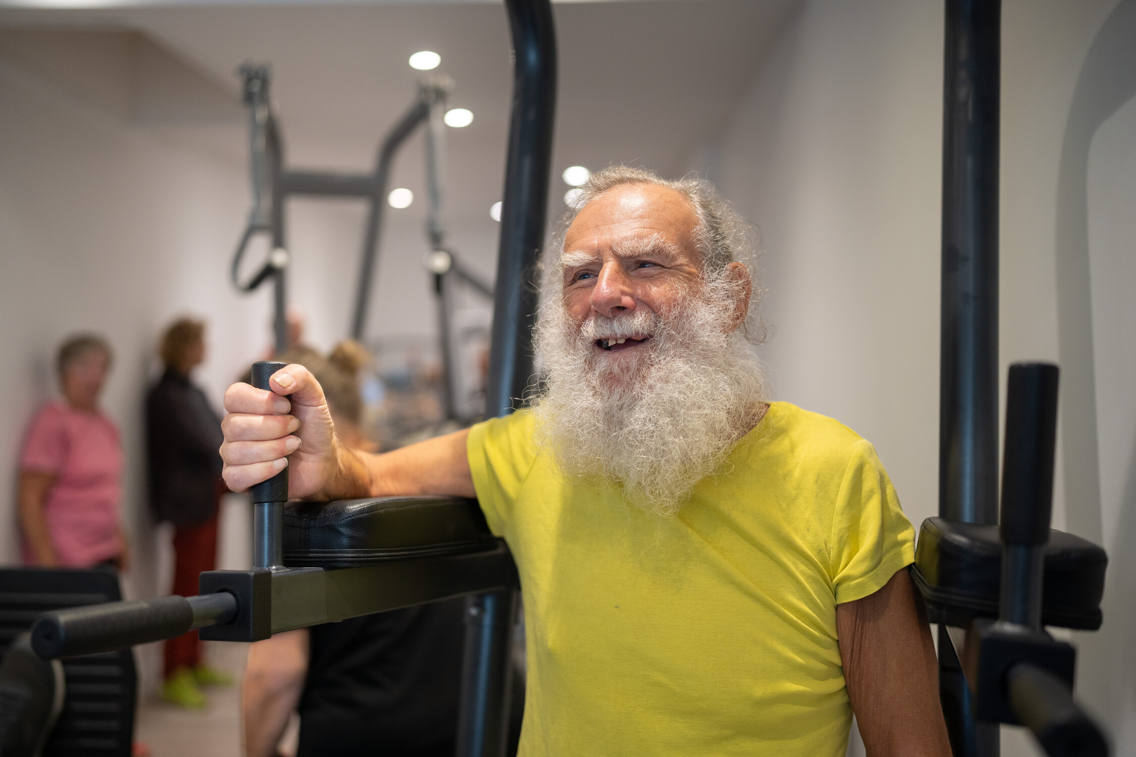Gym Older man is using a machine at a gym and smiling