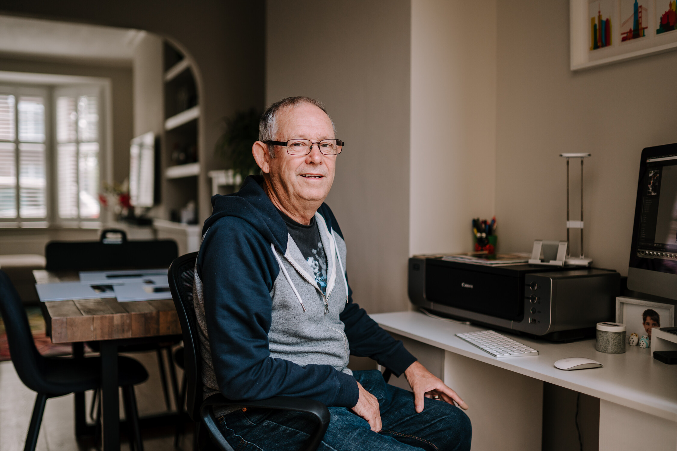 Man is sat at home at his desk smiling