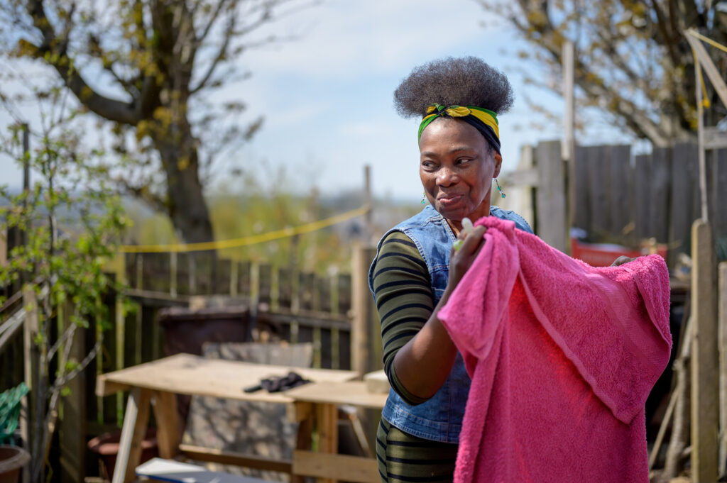 Woman in her garden putting laundry on the line.