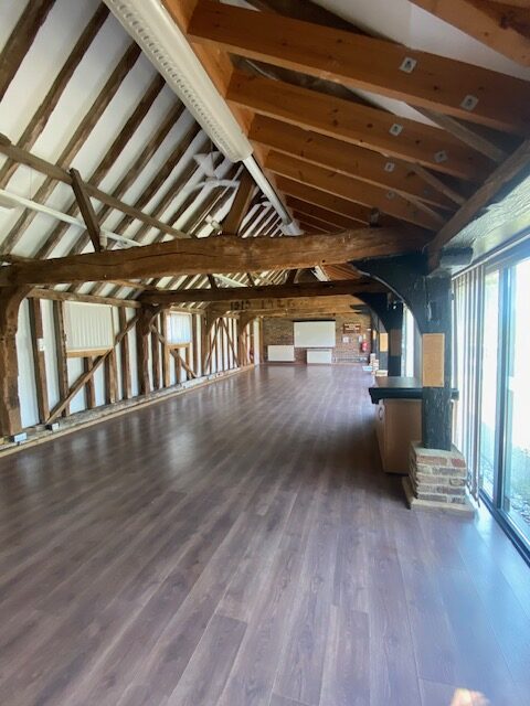 The education room at Thames Chase Forest Centre, it's a spacious room with wooden beams, dark wood floor, large windows, and a whiteboard at the far end.