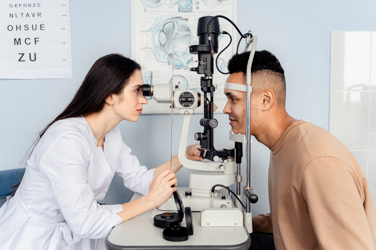 An optometrist looking into the eyes of a man in an opticians office.