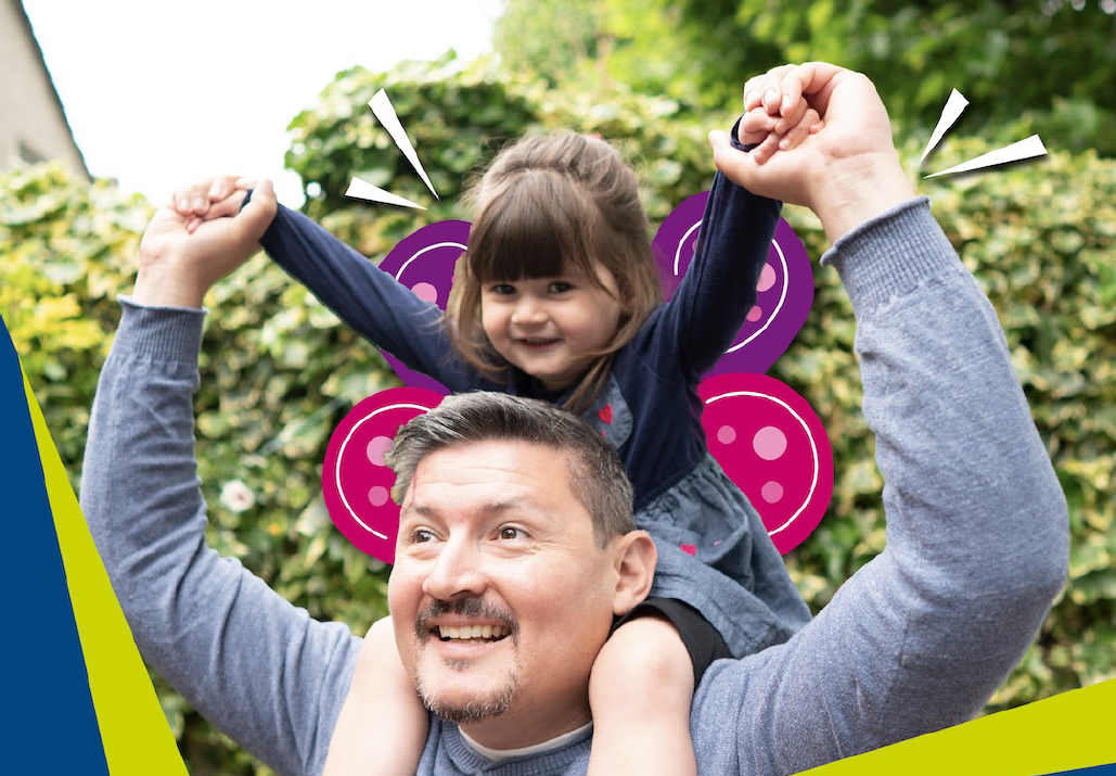 A smiling man carries a cheerful young girl on his shoulders. The girl has illustrated pink butterfly wings and white lines drawn behind her, highlighting her playful pose. They are outdoors with greenery in the background.