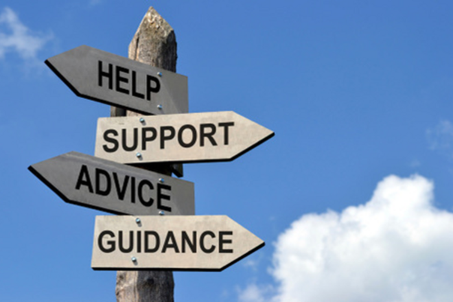 Wooden post with directional signs reading 'HELP,' 'SUPPORT,' 'ADVICE,' and 'GUIDANCE' against a blue sky.