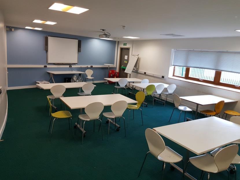 Large meeting room with tables, chairs, and a whiteboard.