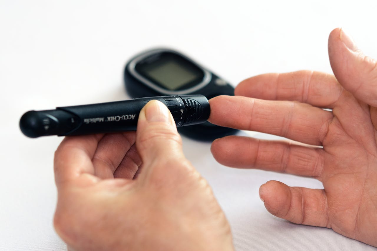 Person using a device to check blood glucose, with the meter blurred in the background.