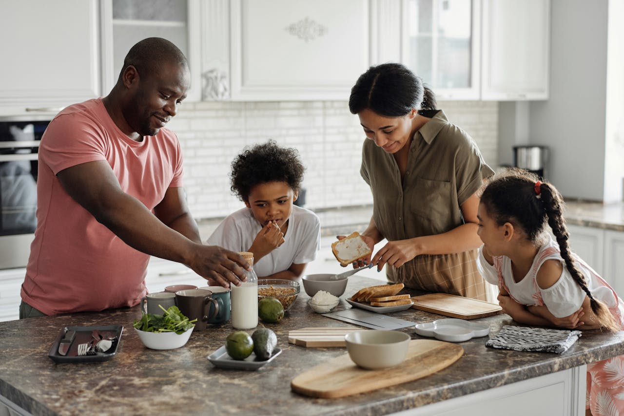amily of four preparing food in a bright kitchen with ingredients on the counter.