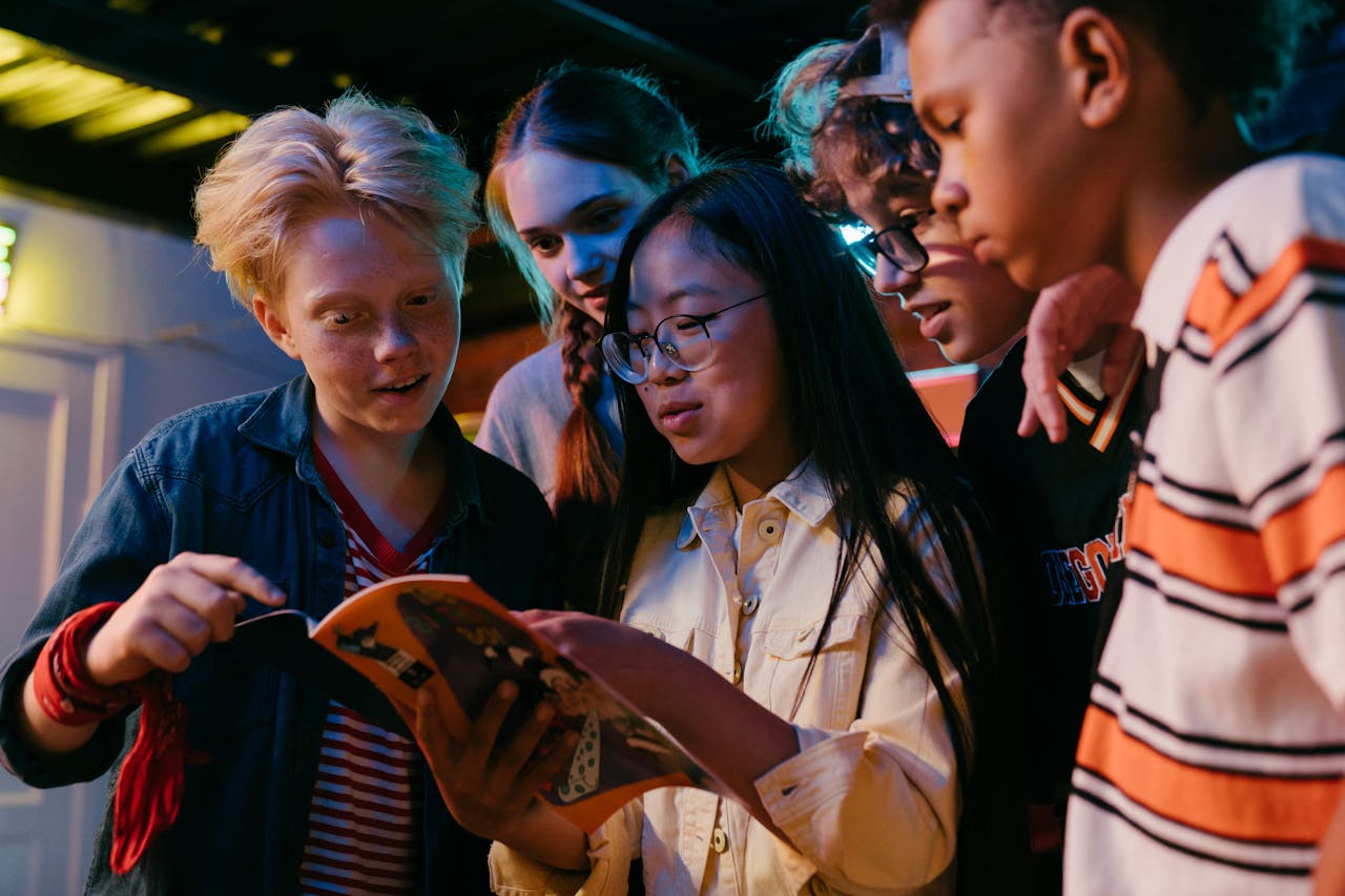 Group of children looking at an open magazine in a dark room.
