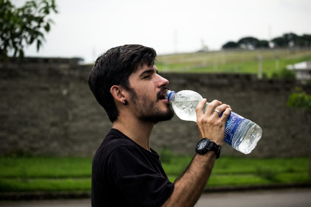 Man in a park is drinking water.