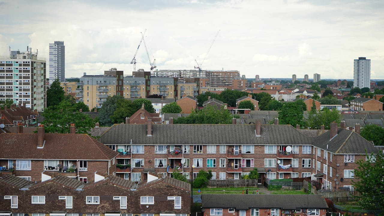 A London skyline with houses, cranes, and blocks of flats in sight.