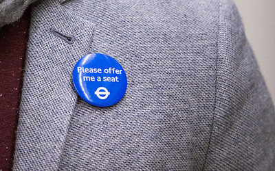please-offer-me-a-badge_rdax_400x250 Someone has the 'Please offer me a seat' badge on their grey suit jacket.