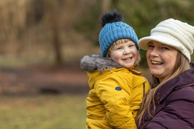 A mum and son together in a park smiling
