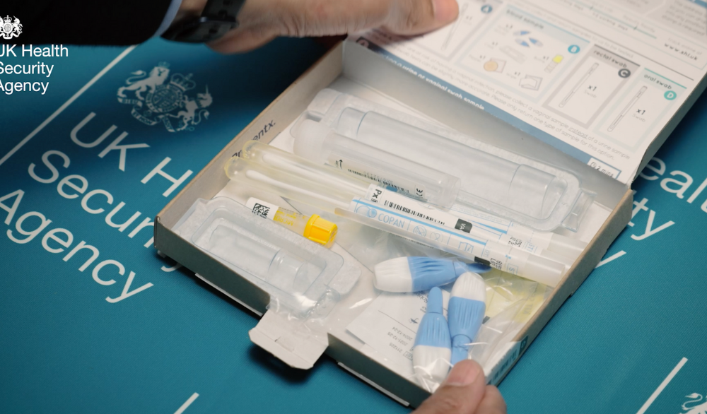 An open STI test kit in a cardboard box.