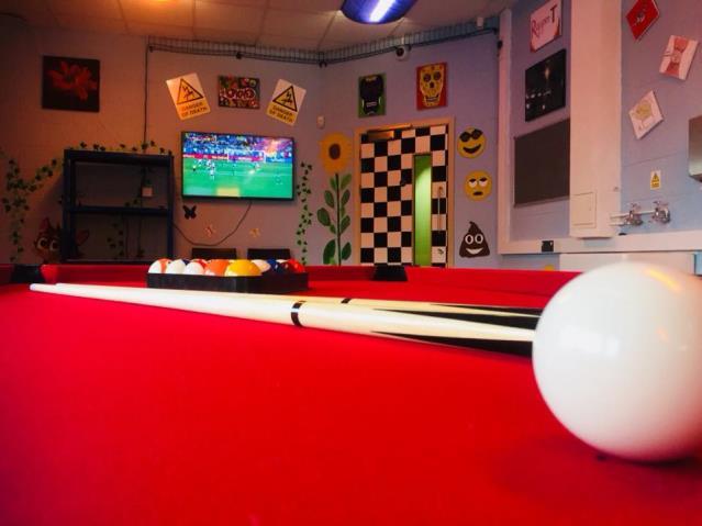 Youth lounge with a red pool table and gaming set up.