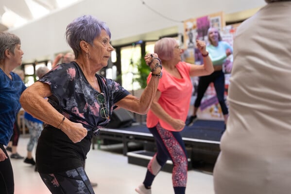 Two women dancing in a zumba class at an indoor community centre.