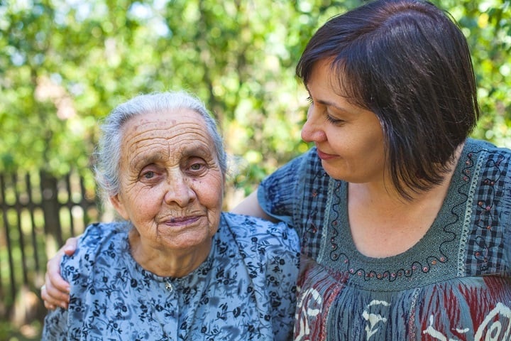 A younger lady with her arm around an older lady.