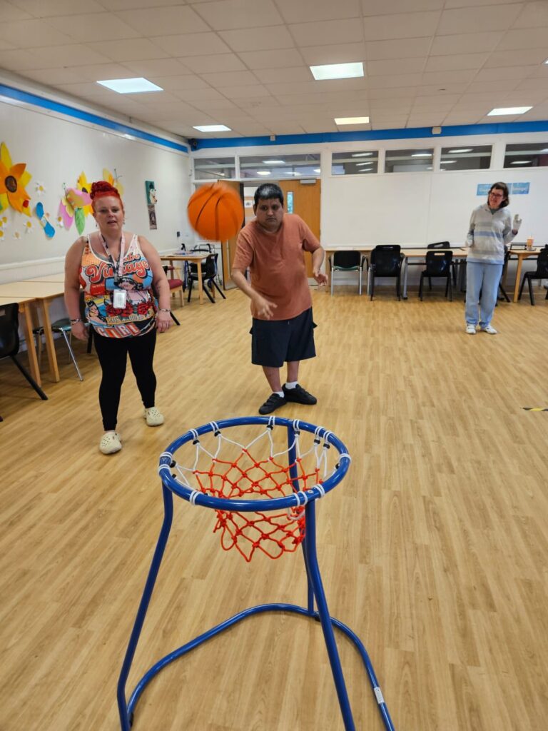 3 adults together in a hall playing basketball