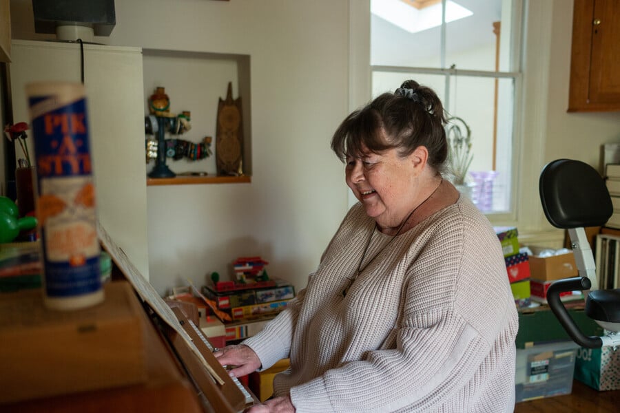Woman playing a piano in her living room.