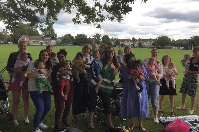 A group of mums and babies together in a park posing for a photo