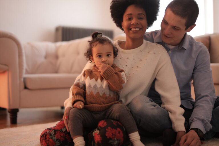 A mother and father sitting side by side with their toddler on mother's lap.