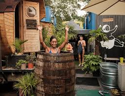 A woman smiling in a cold plunge barrel outside the community sauna.