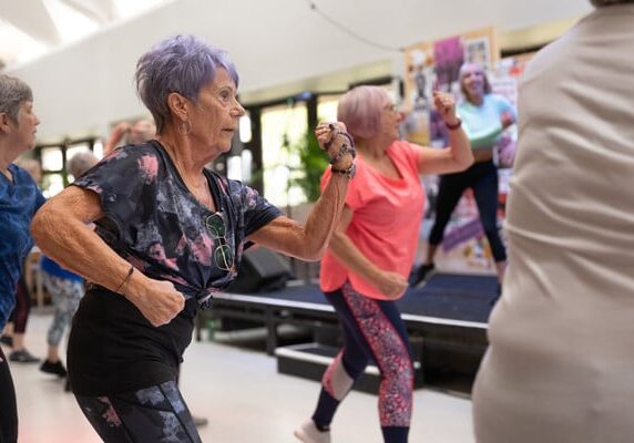Two women dancing in a zumba class at an indoor community centre.
